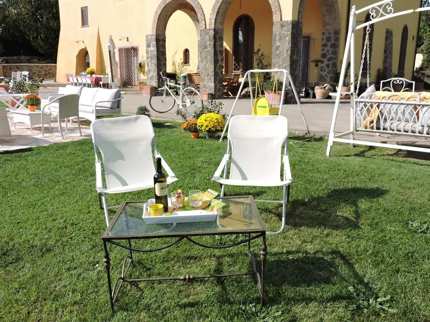 Two chairs and a table on the lawn, with the swing
